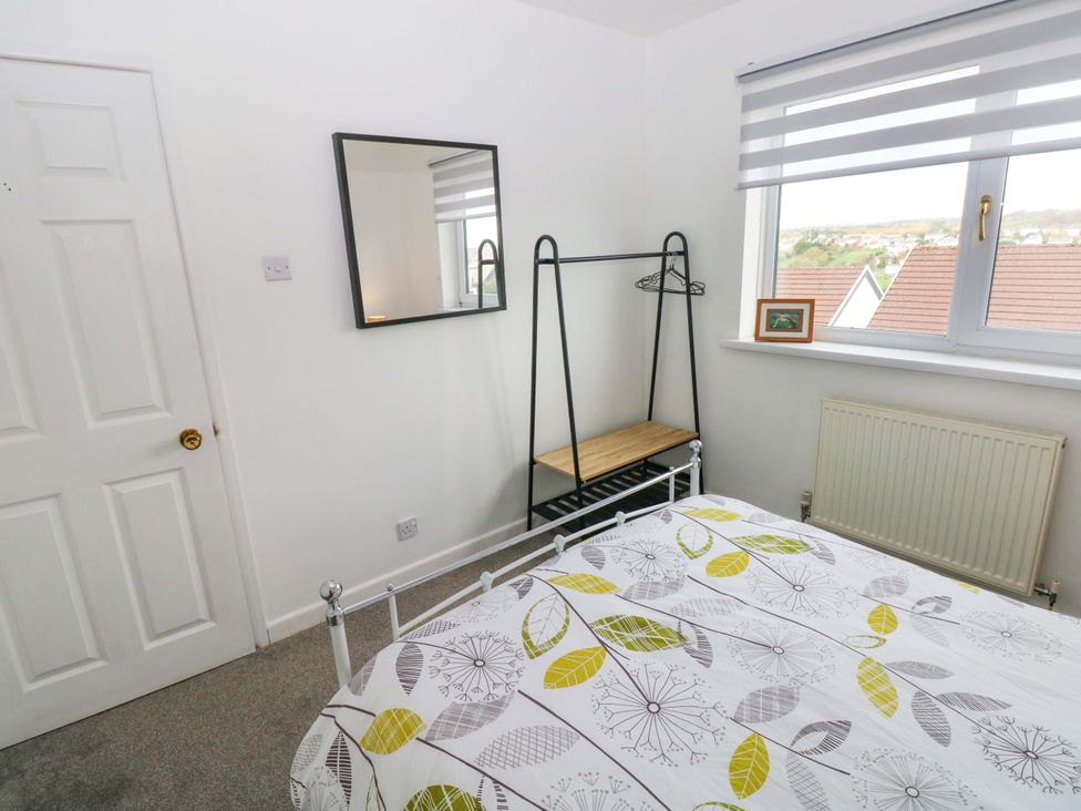 A bedroom with a bed, mirror and window at 15 Lawnswood Saundersfoot