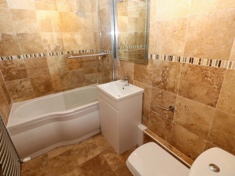A bathroom with a bathtub, sink, and toilet at 15 Lawnswood in Saundersfoot