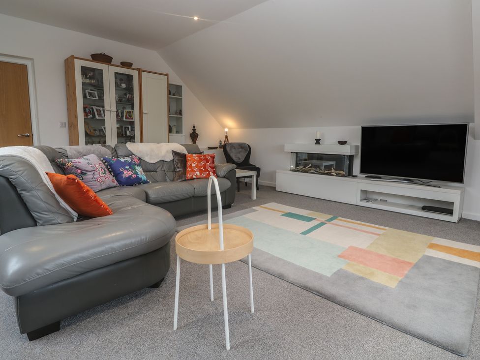 A living room with a sofa and television at Chy Holly in Carbis Bay
