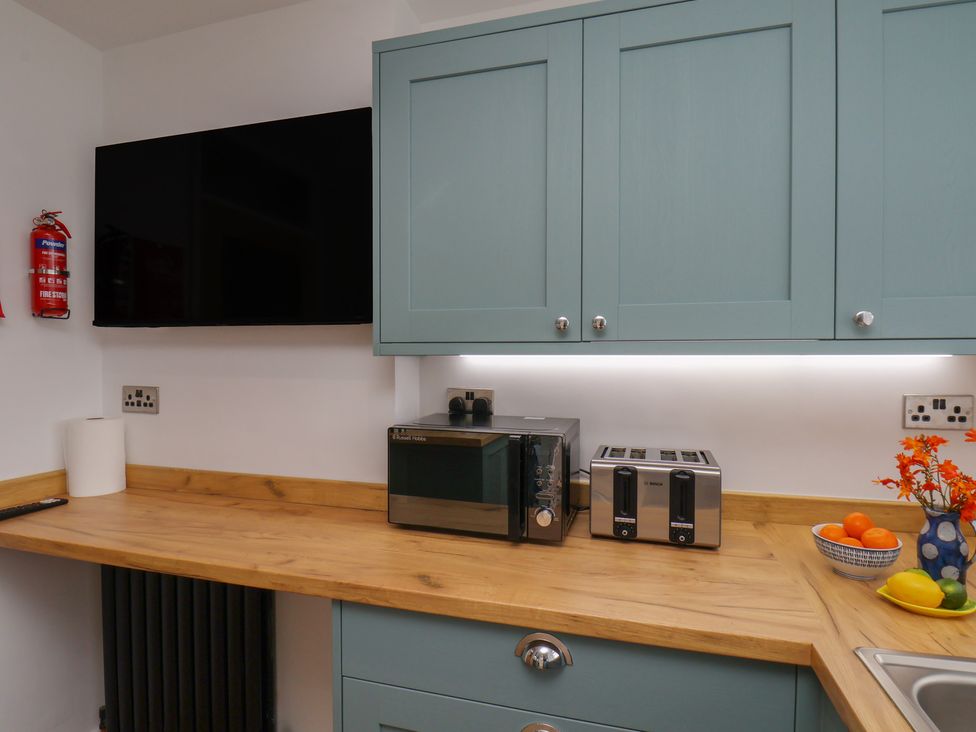 A kitchen with a microwave, toaster, and TV at Sea Roke in Filey