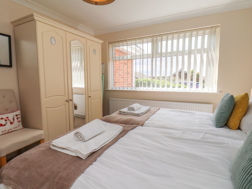 A bedroom with two beds and a wardrobe at Sea Roke in Filey