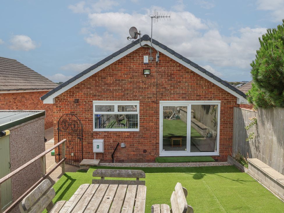 A garden with a brick house and outdoor seating at Sea Roke in Filey