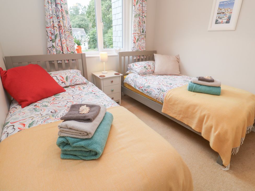 A bedroom with two single beds and a nightstand at Jaspers Retreat, formerly known as Starfish Cottage, Falmouth