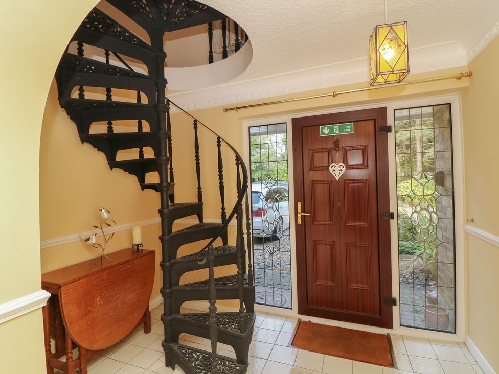 A hallway with a spiral staircase and front door at Larkspur Cottage in Alford