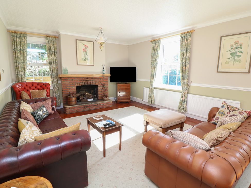 A living room with sofas, a fireplace, and a television at Larkspur Cottage in Alford
