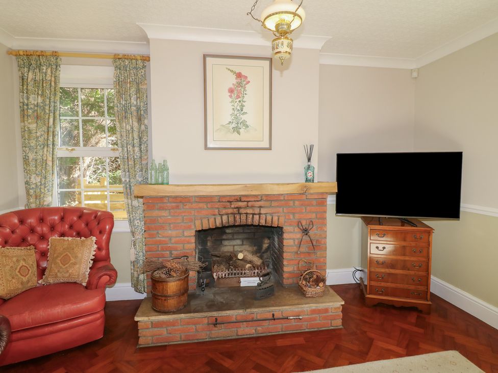 A living room with an armchair and television at Larkspur Cottage in Alford