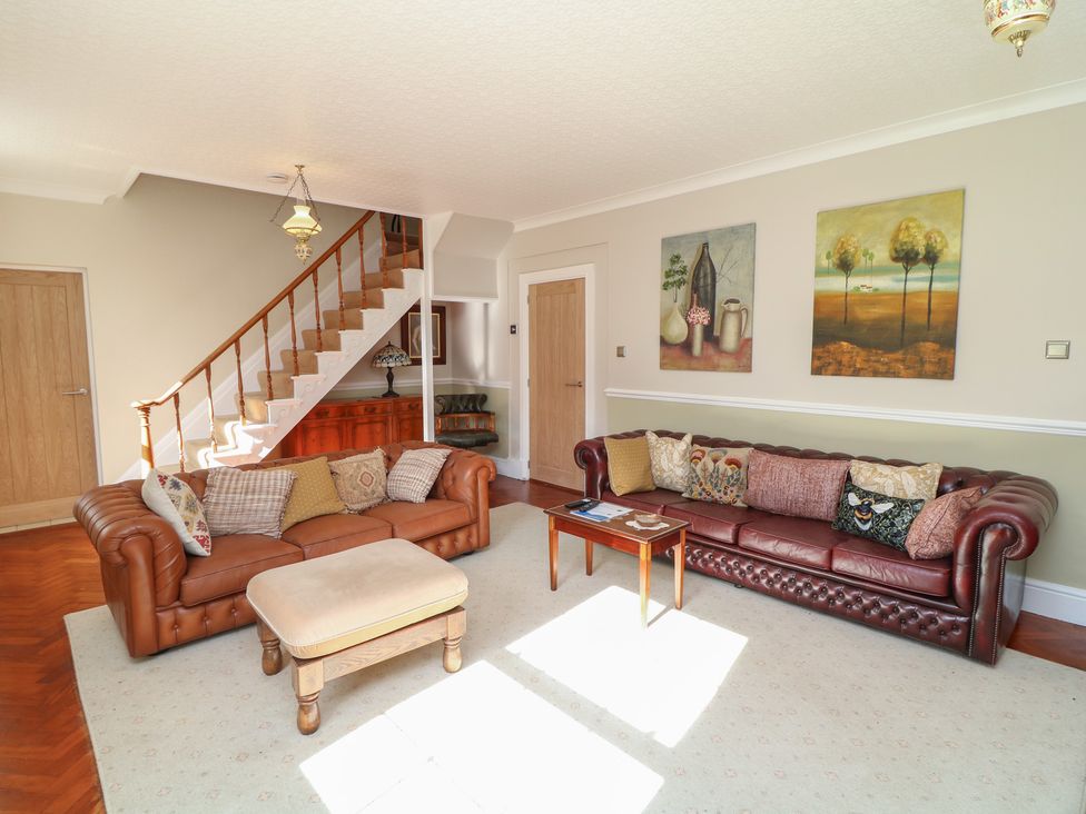 A living room with sofas and a table at Larkspur Cottage in Alford
