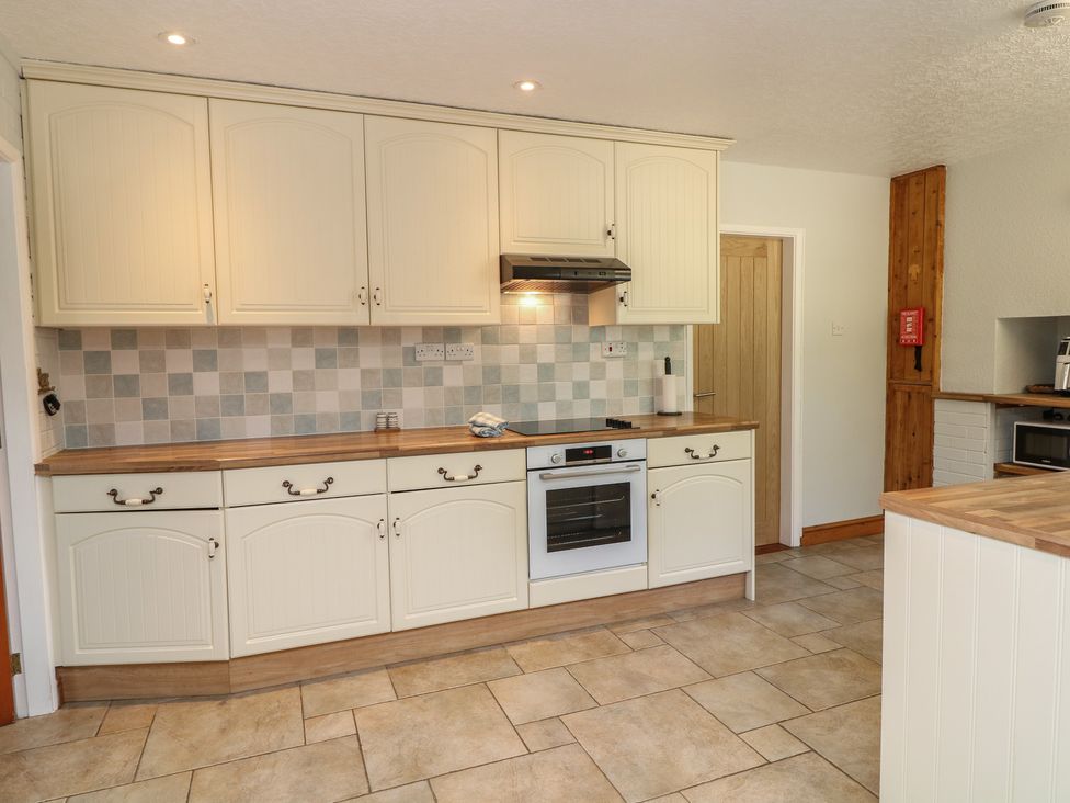 A kitchen with cabinets and oven at Larkspur Cottage in Alford