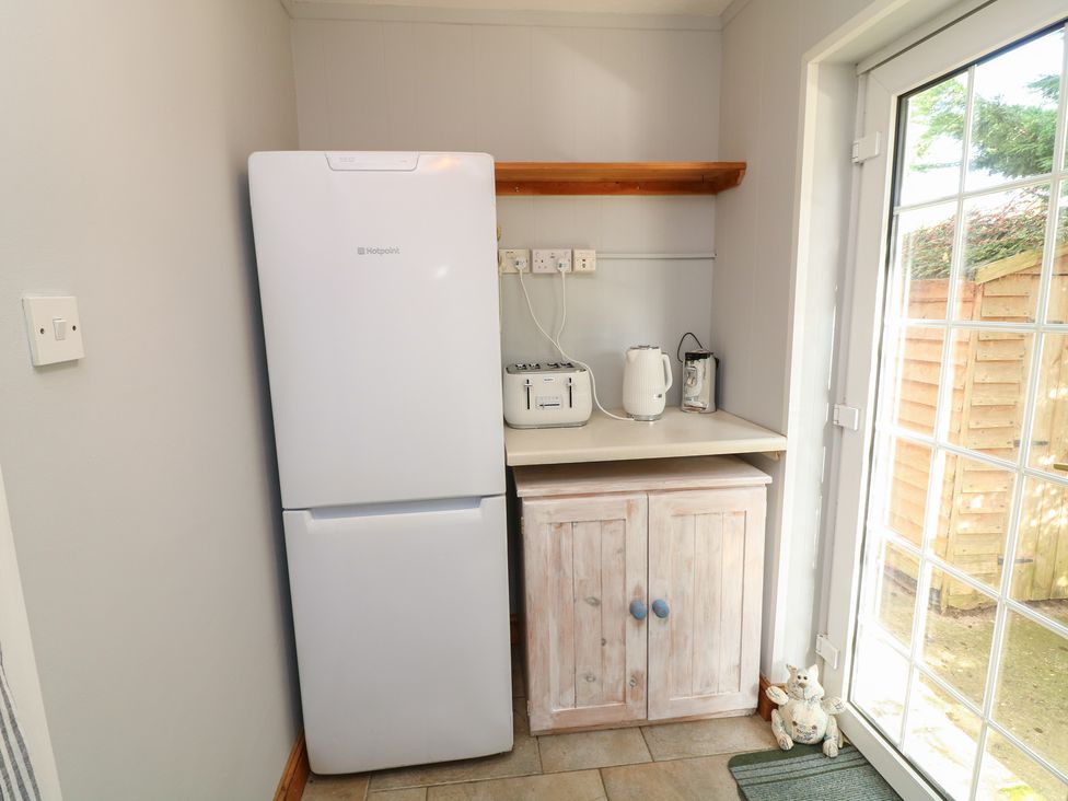 A kitchen with refrigerator, toaster, kettle, and cupboard at Larkspur Cottage in Alford