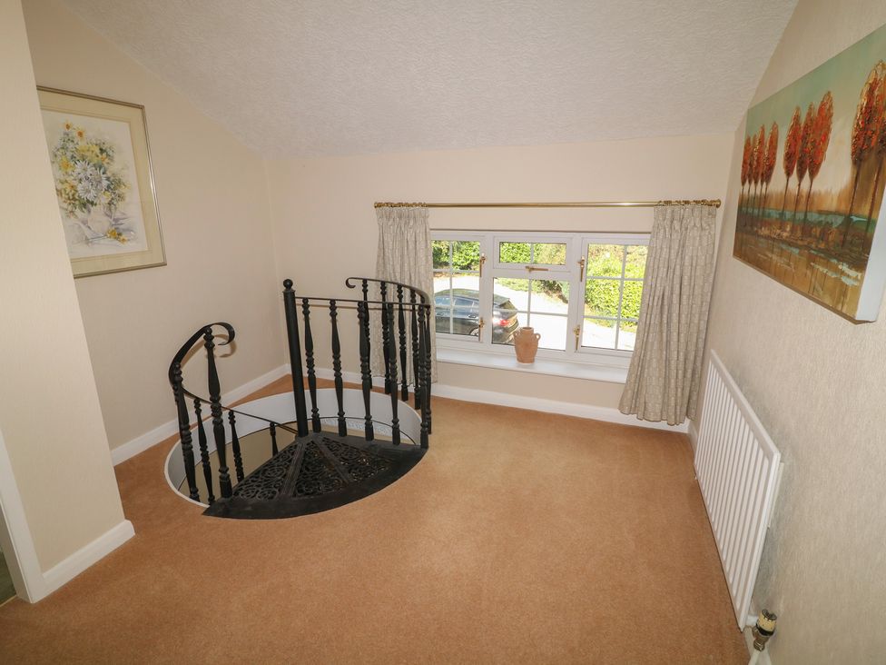 A landing with a spiral staircase and window at Larkspur Cottage in Alford