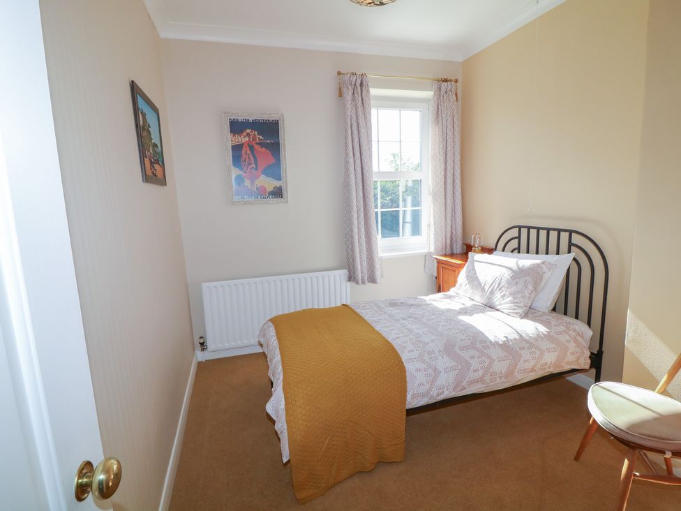 A bedroom with a bed and nightstand at Larkspur Cottage in Alford