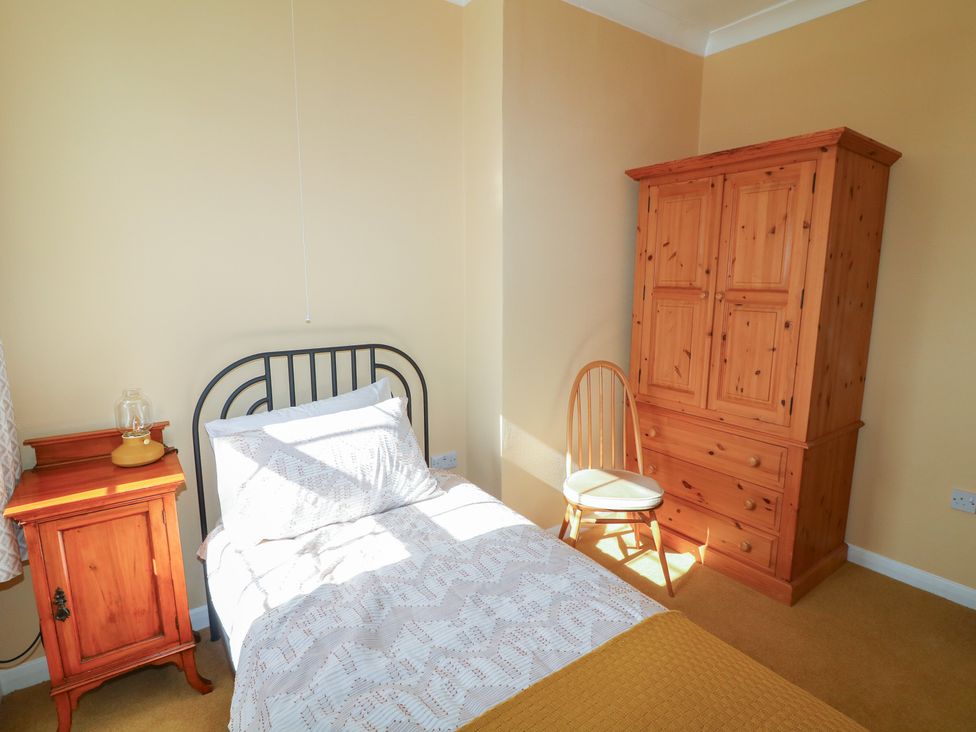 A bedroom with a bed and a wardrobe at Larkspur Cottage in Alford