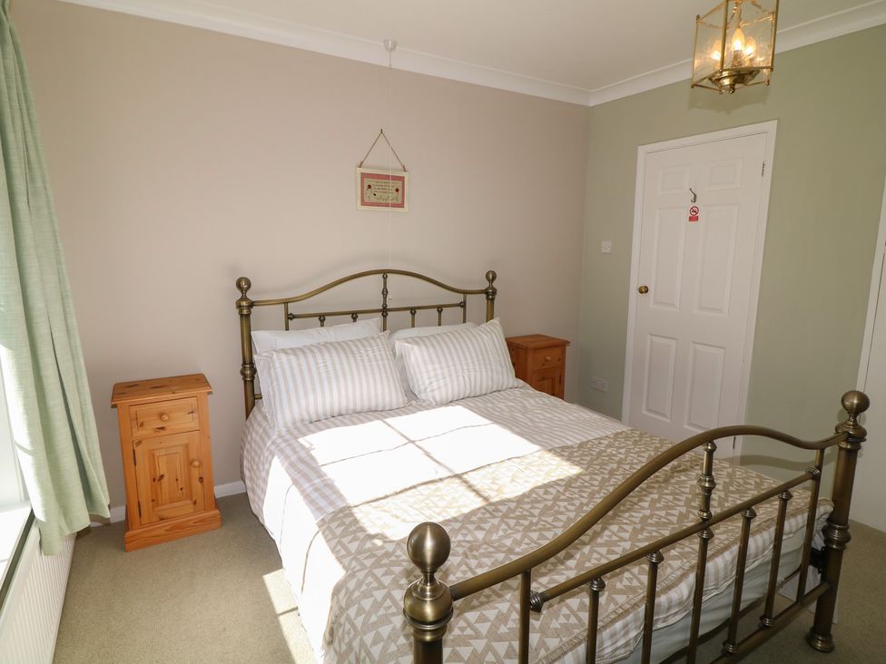 A bedroom with a bed and nightstands at Larkspur Cottage in Alford