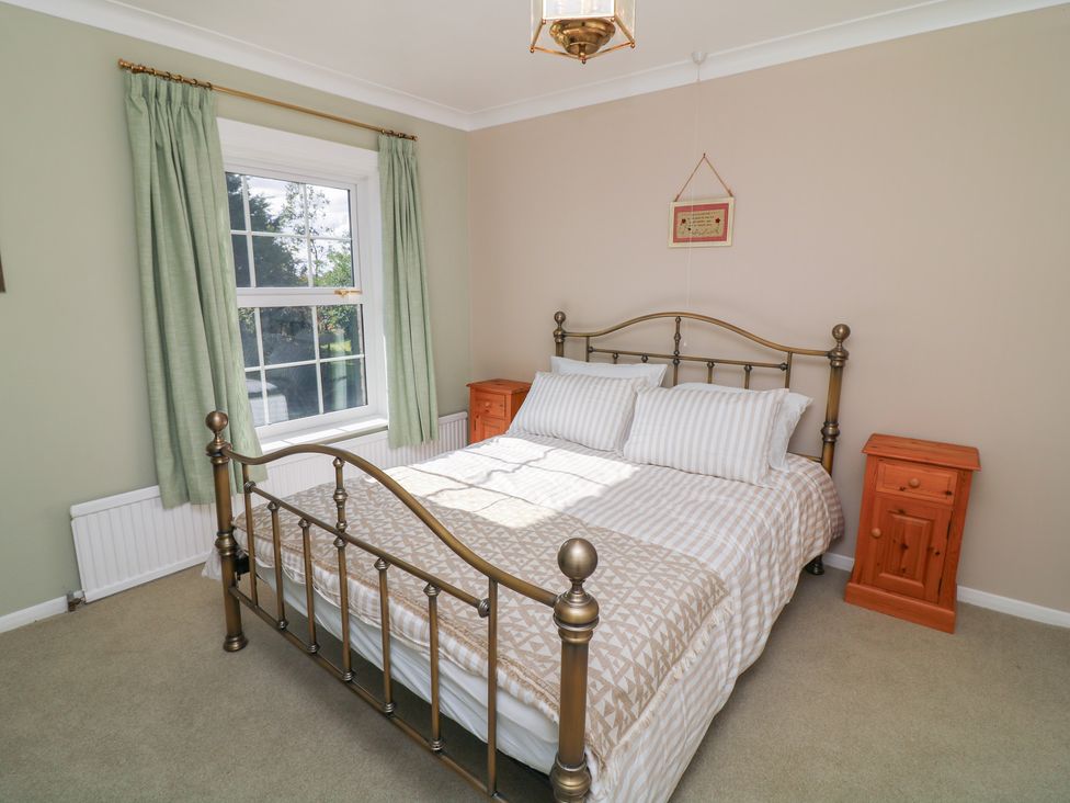A bedroom with a bed and bedside tables at Larkspur Cottage in Alford