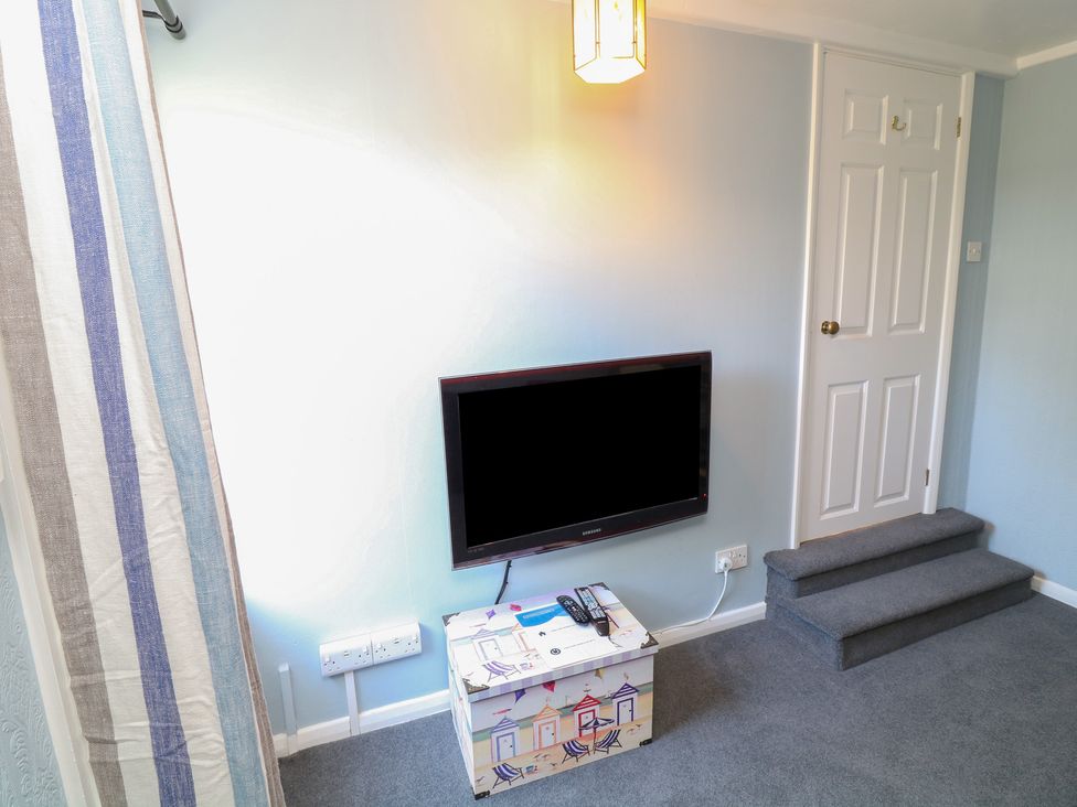A living room with a television and a step at Larkspur Cottage in Alford