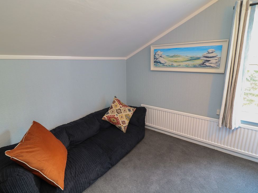 A living room with a sofa, cushion, artwork, and window at Larkspur Cottage in Alford