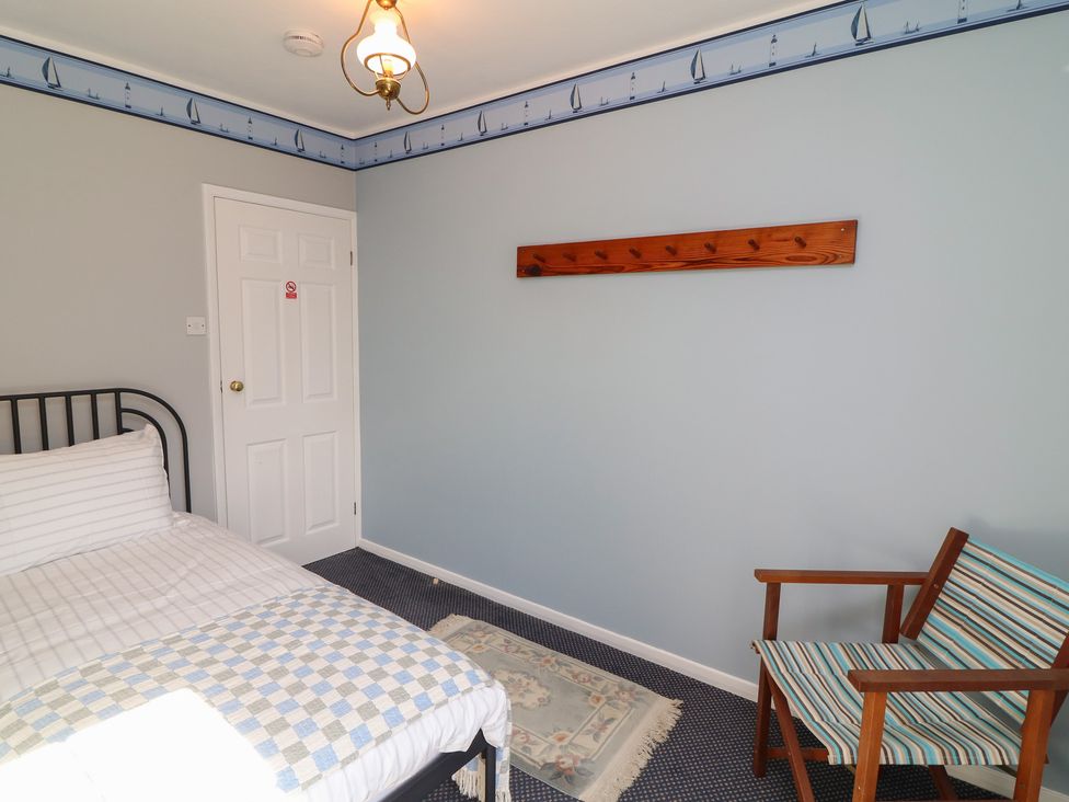A bedroom with a bed and a chair at Larkspur Cottage in Alford