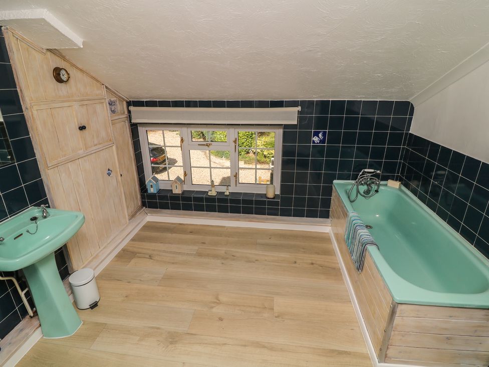 A bathroom with a bathtub, sink, and window at Larkspur Cottage in Alford