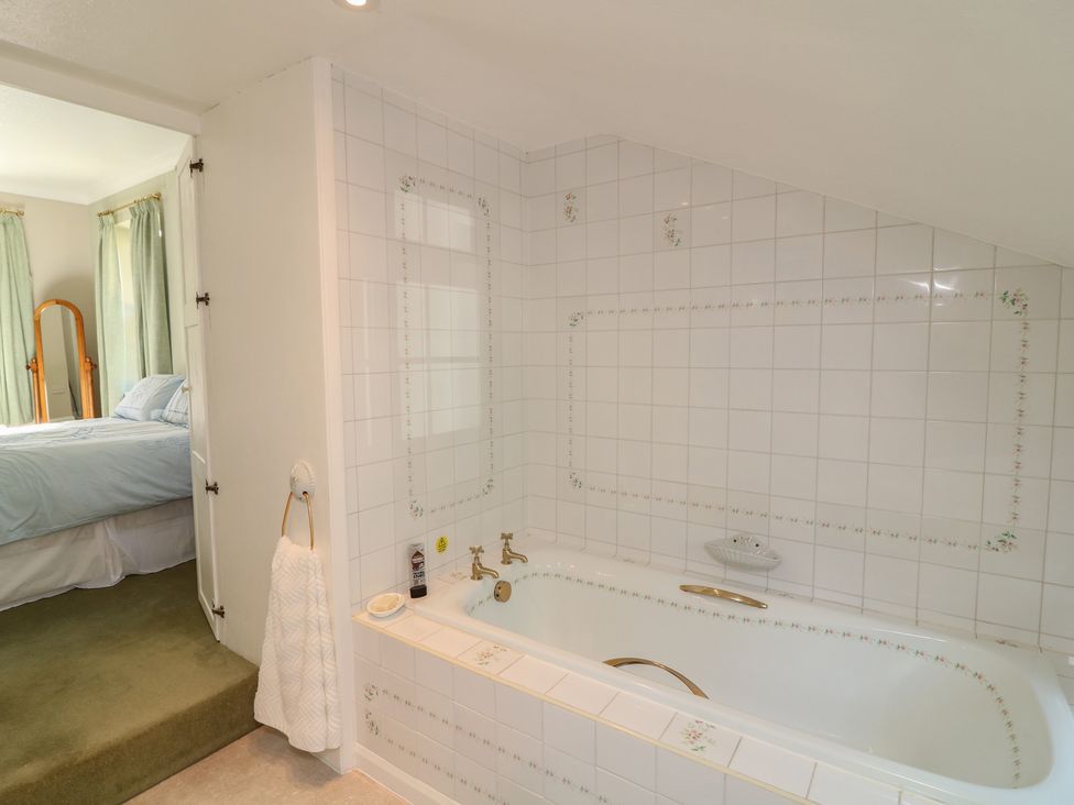 A bathroom with a bathtub and towel rack at Larkspur Cottage in Alford