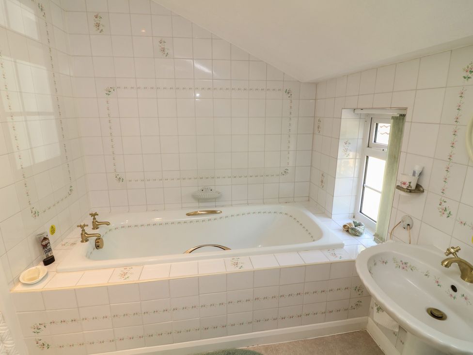 A bathroom with a bathtub and sink at Larkspur Cottage in Alford