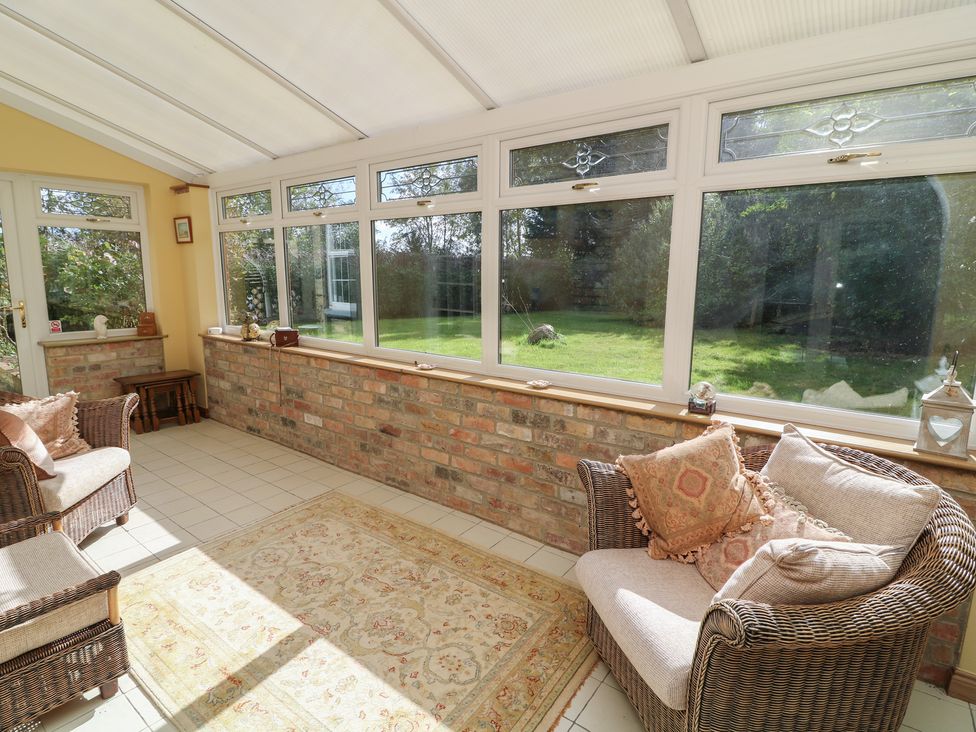 A conservatory with seating and a view of the garden at Larkspur Cottage Alford