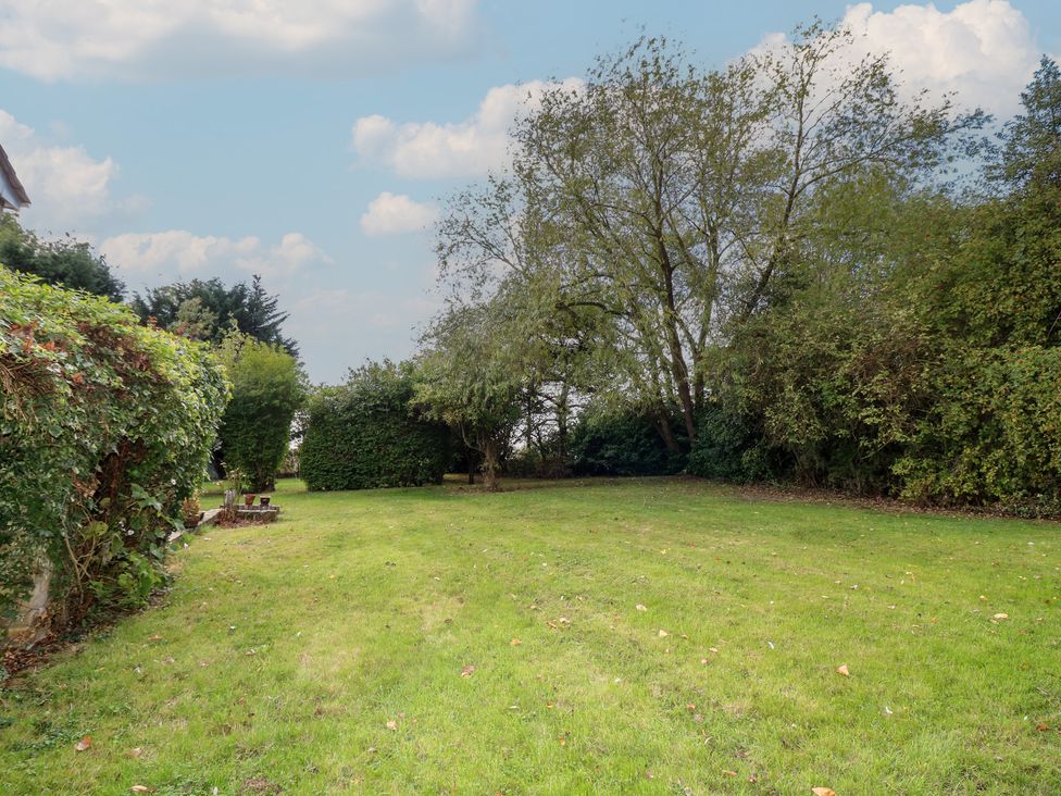 A garden with grass and trees at Larkspur Cottage Alford