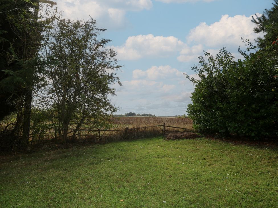 A garden view with grass and trees at Larkspur Cottage Alford