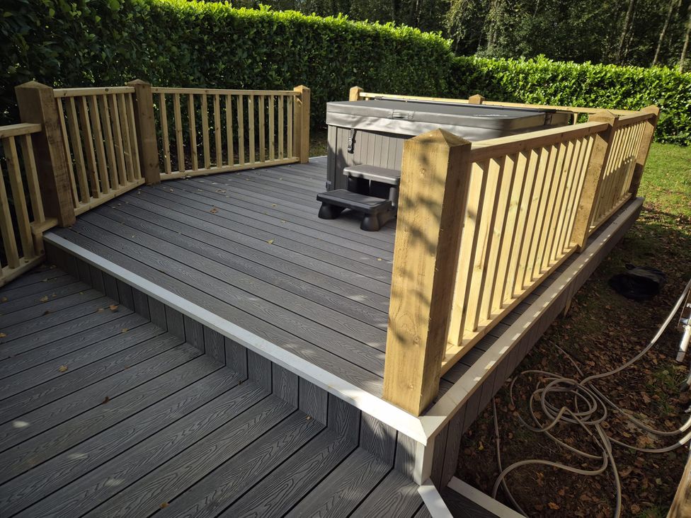 A deck with a hot tub and railing at Willow in Dolton