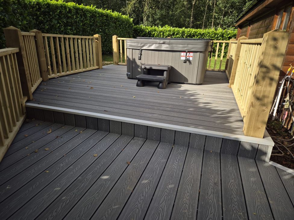 An outdoor deck with a hot tub and wooden railing at Willow in Dolton