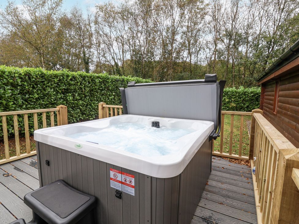 A hot tub on a deck with trees in the background at Willow in Dolton