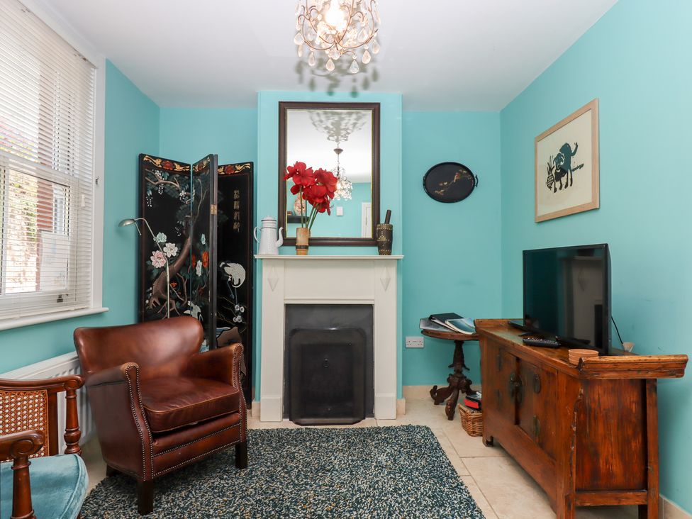 A living room with an armchair and television at 5 Exe Street Topsham