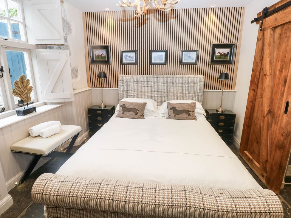 A bedroom with a bed and pictures on the wall at The Stalls at Gileston Manor St Athan