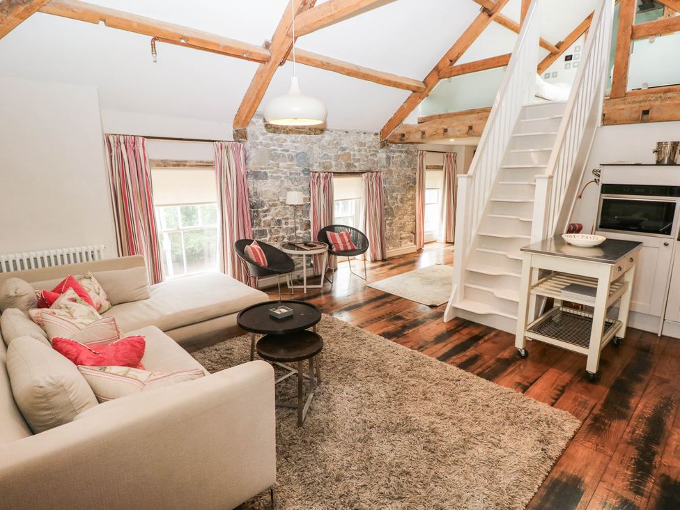 A living room with a sofa and staircase at The Coach House at Gileston Manor near St Athan