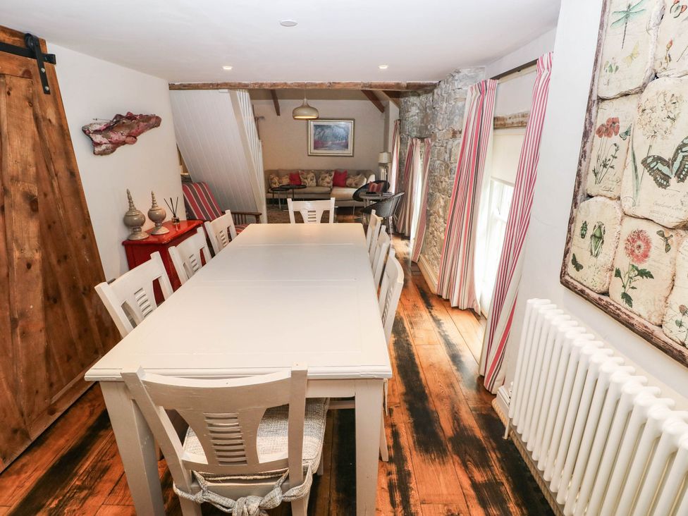 A dining room with a long table and chairs at The Coach House at Gileston Manor near St Athan