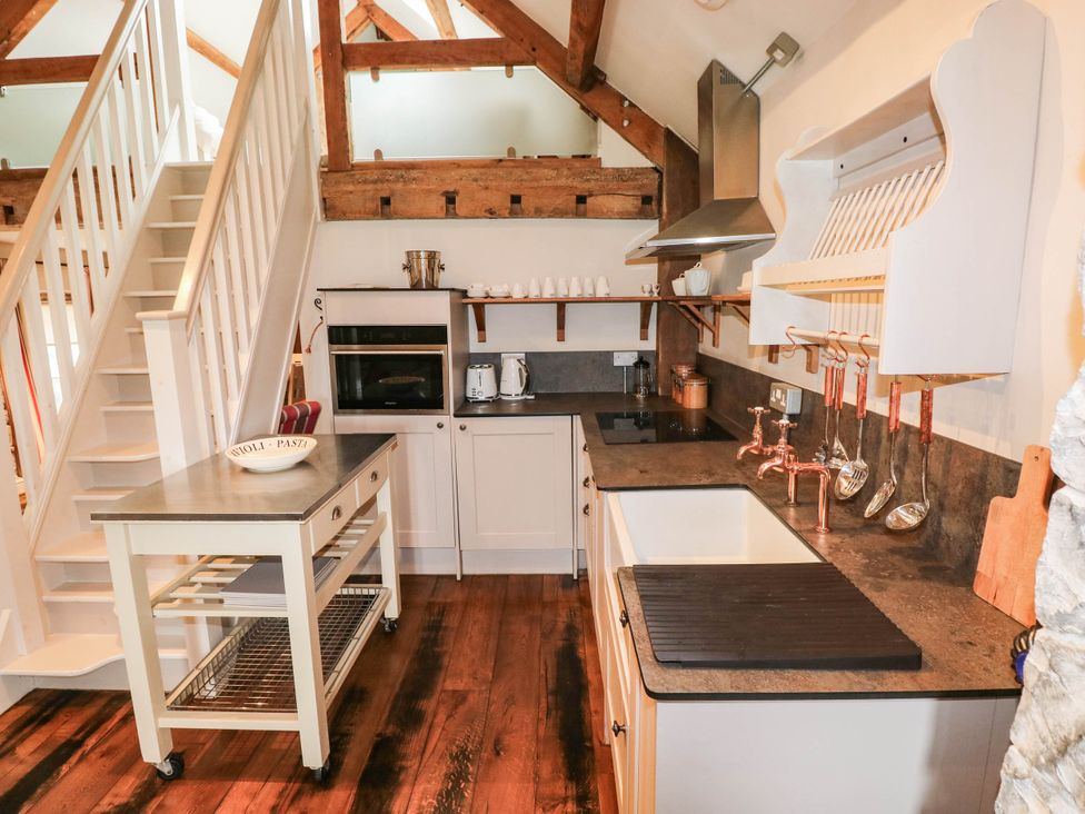 A kitchen with a stove, sink and kitchen island at The Coach House at Gileston Manor near St Athan