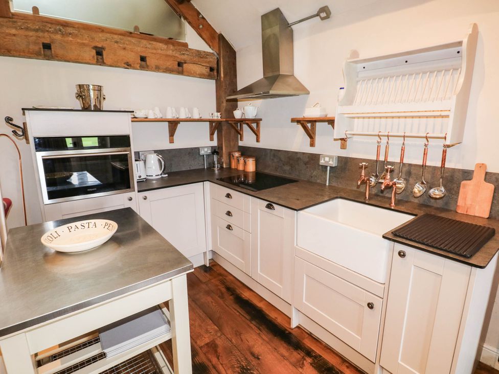 A kitchen with a sink, oven, kettle, and shelves at The Coach House at Gileston Manor near St Athan