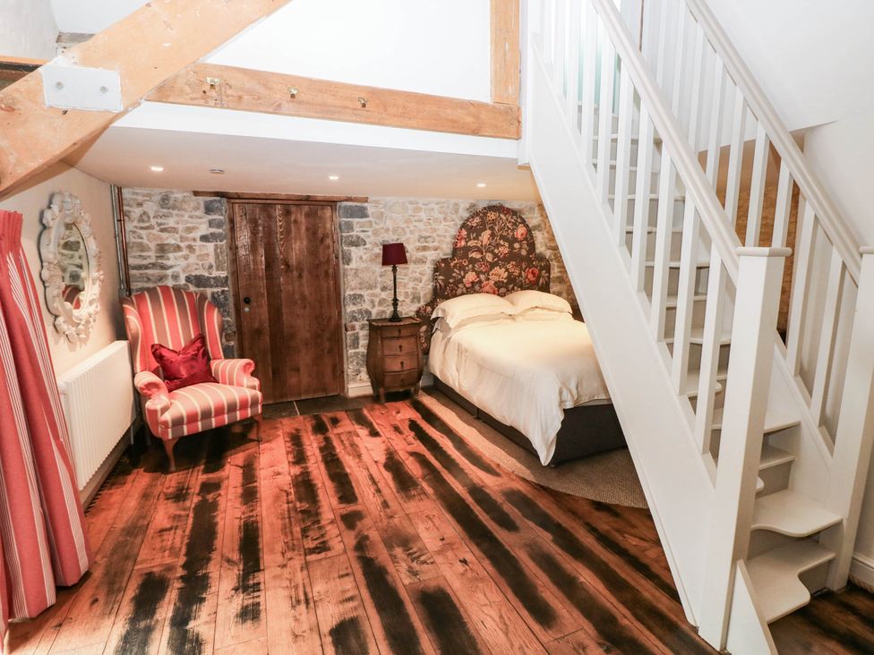 A bedroom with a bed and chair at The Coach House at Gileston Manor near St Athan
