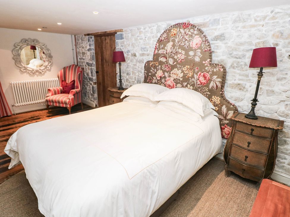 A bedroom with a bed and armchair at The Coach House at Gileston Manor near St Athan