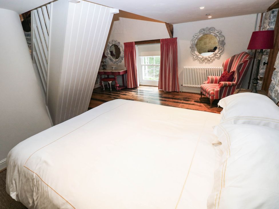 A bedroom with a bed and chair at The Coach House at Gileston Manor near St Athan