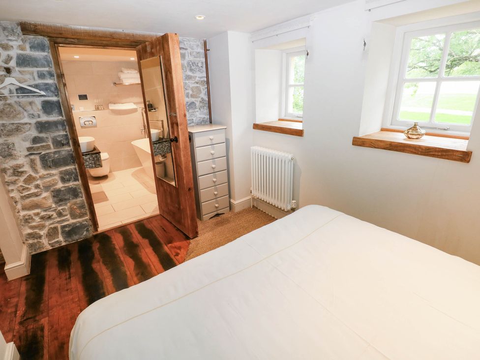 A bedroom with a bed and a bathroom entrance at The Coach House at Gileston Manor near St Athan