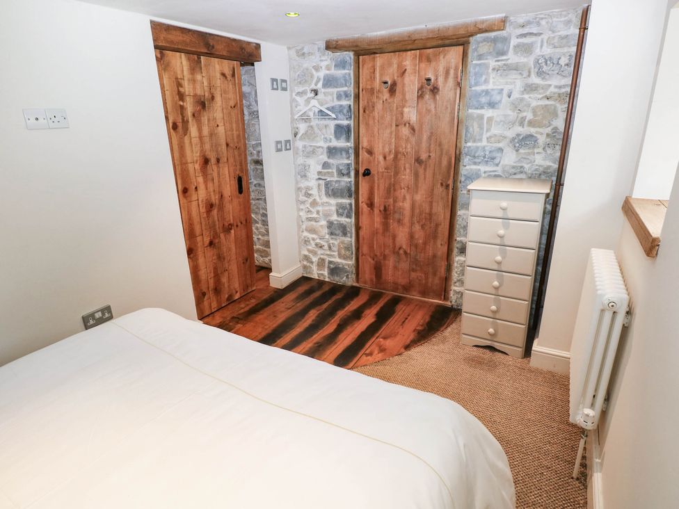 A bedroom with a bed and wooden doors at The Coach House at Gileston Manor near St Athan