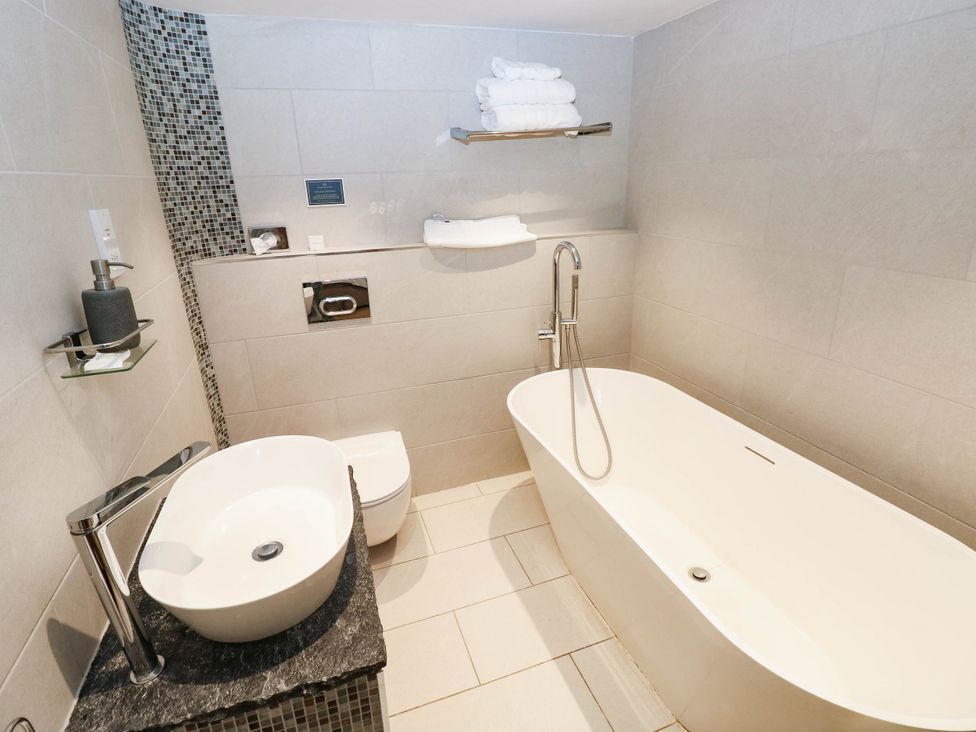 A bathroom with a bathtub, sink, and toilet at The Coach House at Gileston Manor near St Athan