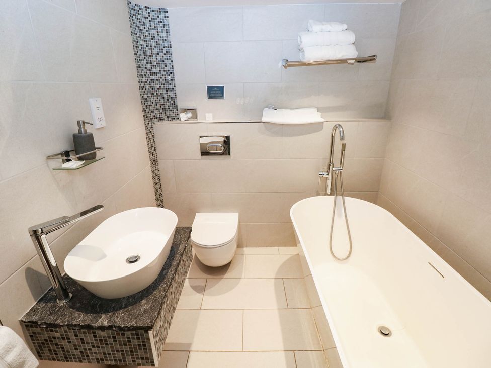 A bathroom with bathtub, washbasin, and toilet at The Coach House at Gileston Manor near St Athan