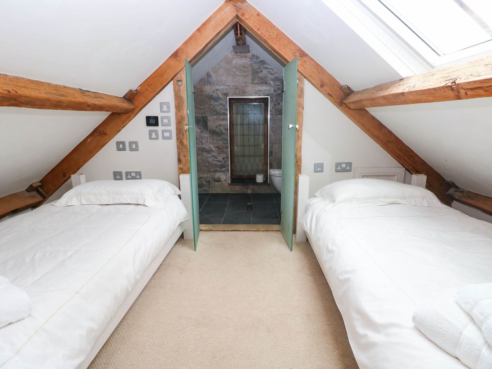 A bedroom with two beds and a bathroom at The Coach House at Gileston Manor near St Athan