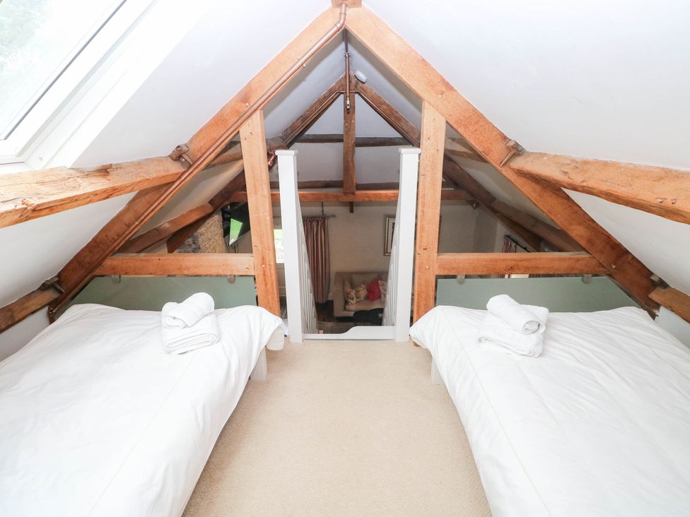 A loft with two beds and wooden beams at The Coach House at Gileston Manor near St Athan