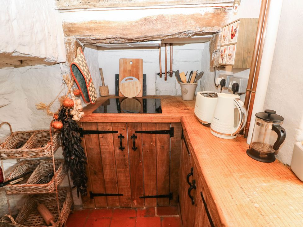 A kitchen with wooden cabinets, countertop, and appliances at The Cheese House at Gileston Manor near St Athan