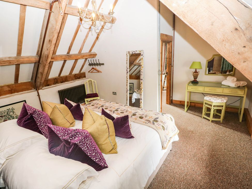 A bedroom with a bed and a mirror at The Cheese House at Gileston Manor near St Athan