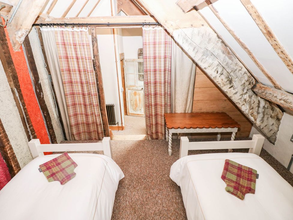 A bedroom with two beds and a wooden table at The Cheese House at Gileston Manor near St Athan