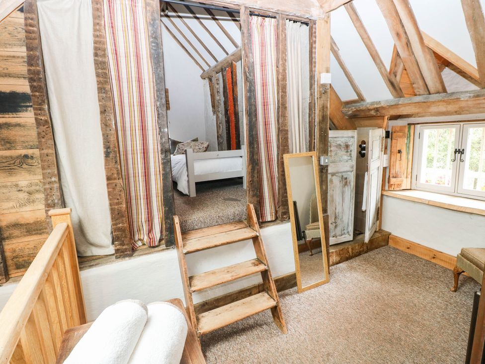 A loft bedroom with stairs and a window at The Cheese House at Gileston Manor near St Athan