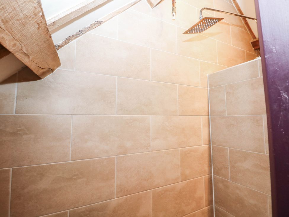 A shower with tiles and wooden beams at The Cheese House at Gileston Manor near St Athan